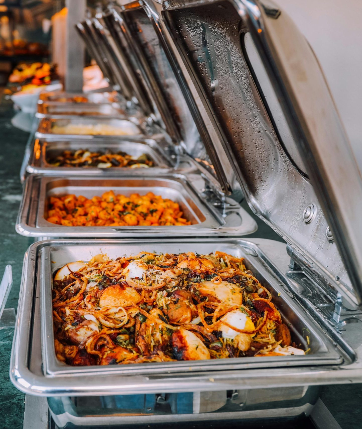 An elegant buffet setup featuring various delicious dishes in stainless steel chafing dishes, perfect for events.